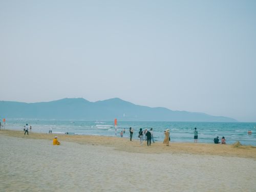 Free A serene beach in Vietnam with visitors enjoying the coastal scenery and distant mountains. Stock Photo