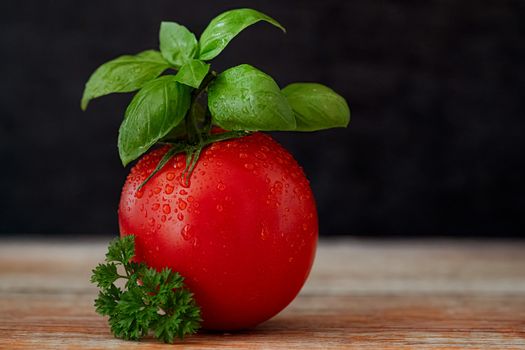 Juicy red tomato with basil leaves and parsley, perfect for healthy cooking and summer salads.