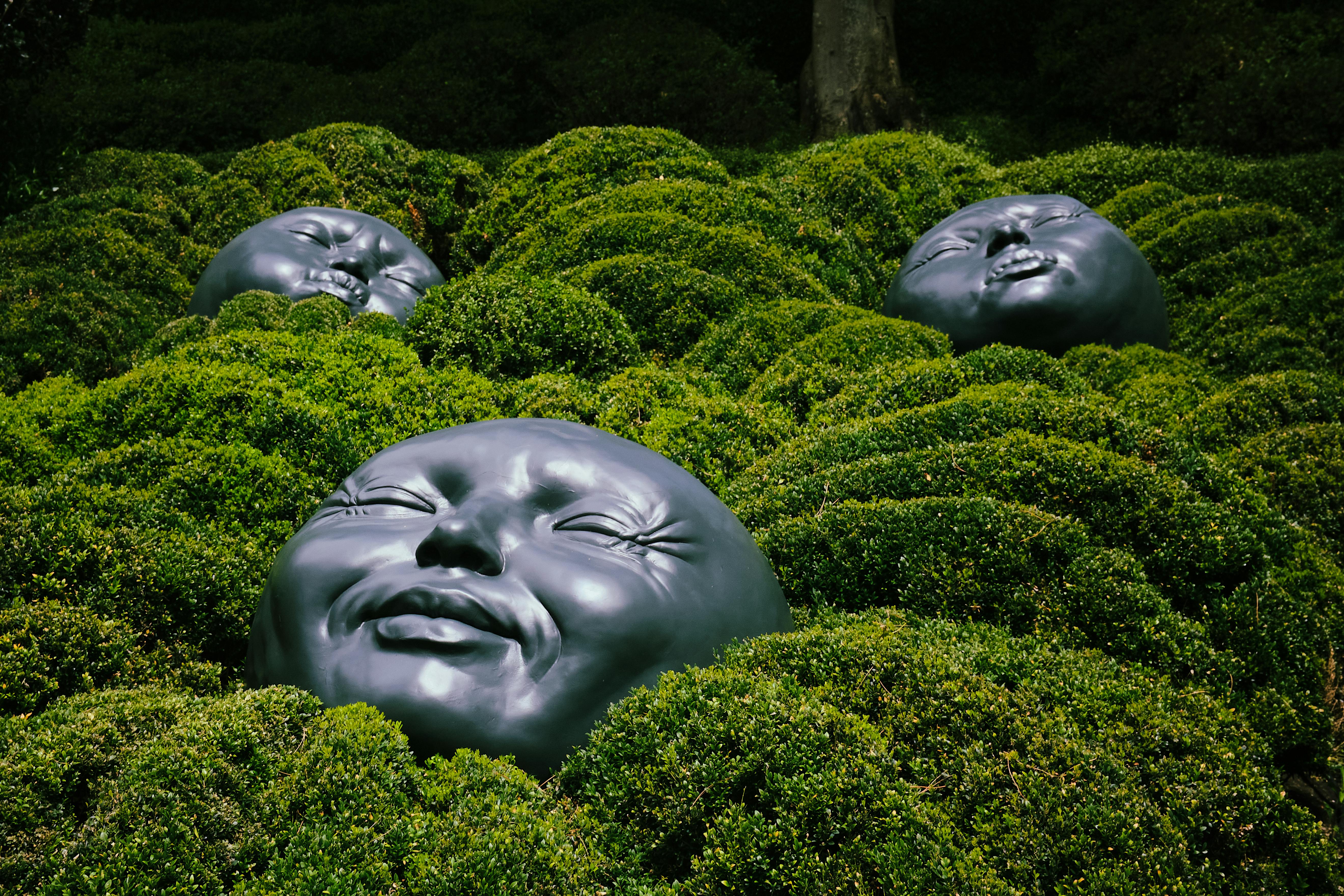 Unique black sculptures nestled in lush greenery at Étretat Gardens, France, showcasing artistic creativity.
