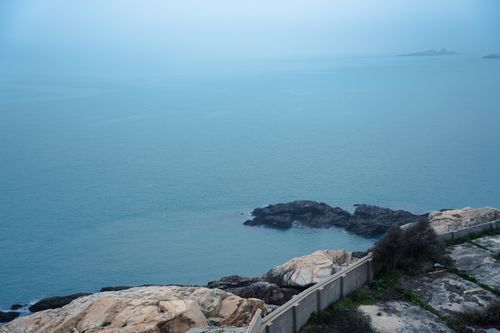 Free A tranquil coastal landscape featuring rocky cliffs and a calm sea under a blue sky. Stock Photo