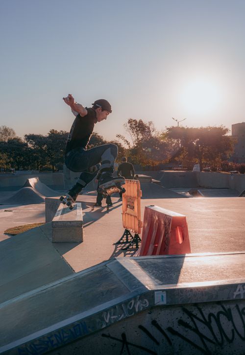 Free A skateboarder performs a trick at a skatepark during sunset, capturing the vibrant skate culture. Stock Photo