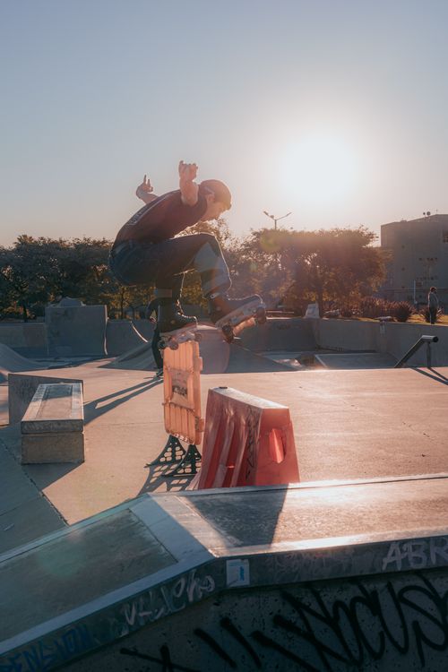 Free A skillful skateboarder executes a jump trick in a skate park during a vibrant sunset. Stock Photo