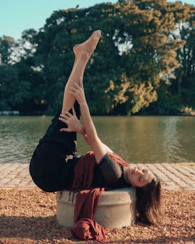 Woman performs yoga by a serene lake in Buenos Aires under the sun.