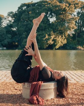 A woman practicing yoga by a lake in Buenos Aires, Argentina, embracing peace and nature.