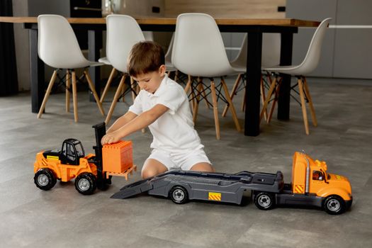 Young boy engaged with toy vehicles on a floor in a modern indoor setting, showcasing playtime imagination.