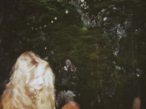 在一张双重曝光的照片里，一位美丽的年轻女子与郁郁葱葱的自然背景融为一体