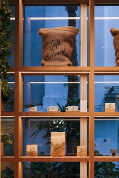 Warm display of Cafe Kitsune coffee bags and cups on wooden shelving with plants.