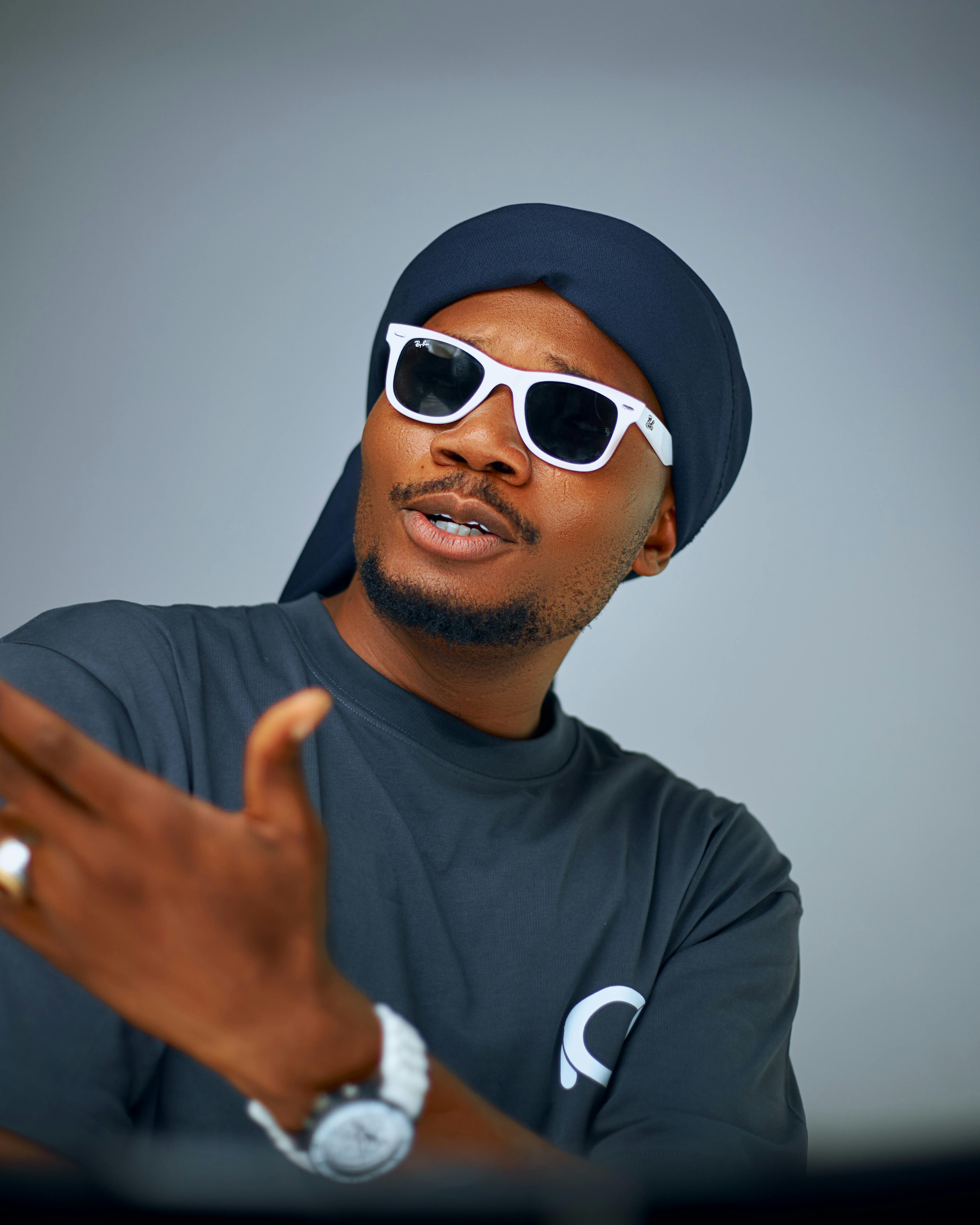 Fashionable man wears sunglasses and a turban, posing confidently indoors.