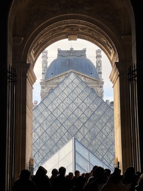 Free Silhouette of people under archway with view of the iconic Louvre Pyramid in Paris. Stock Photo