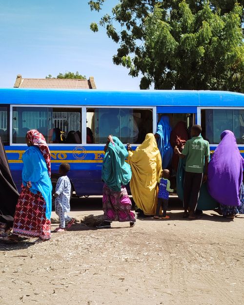 Free Colorful scene of people waiting at a Nigerian bus stop. Daytime outdoor activity. Stock Photo
