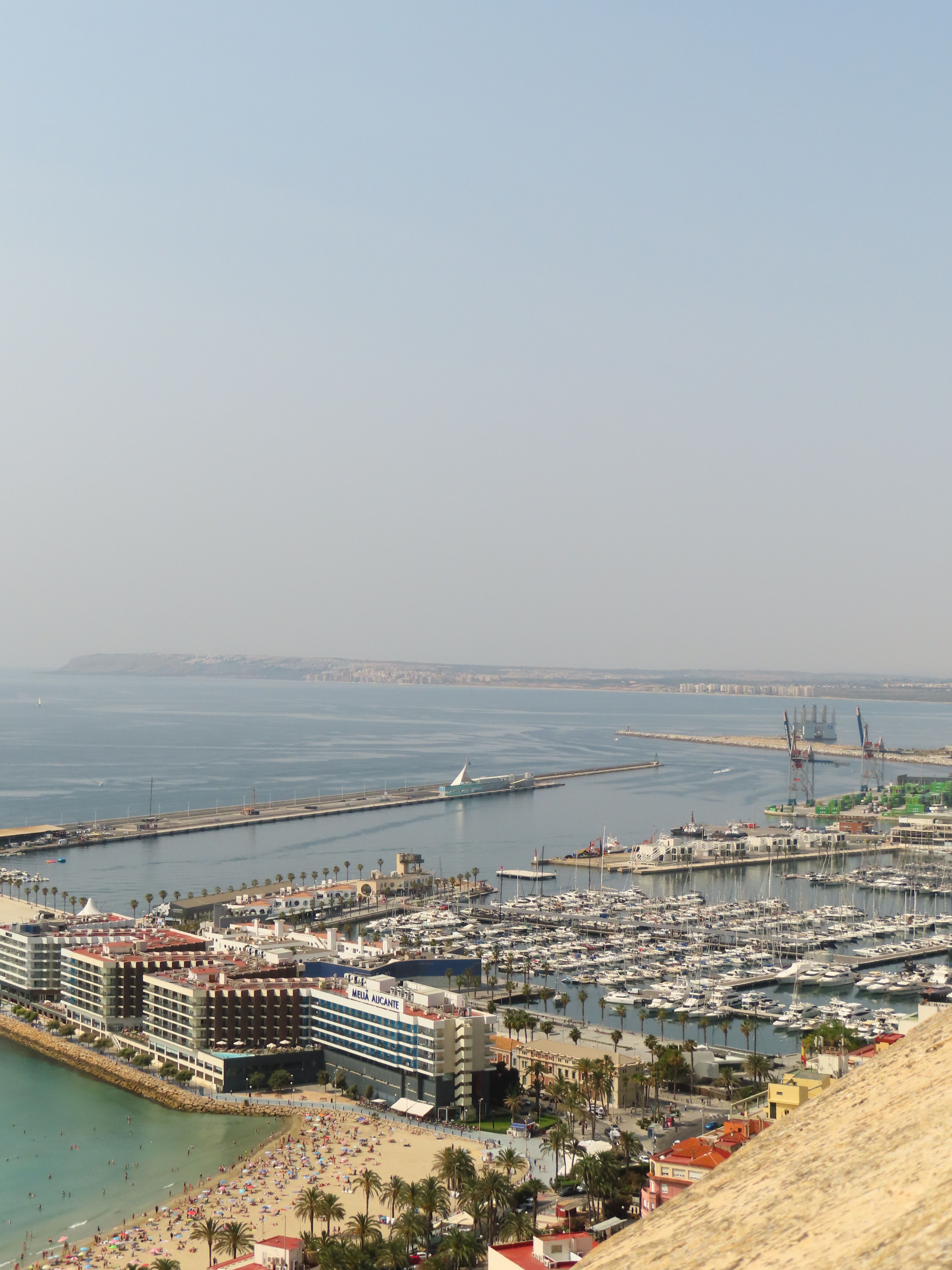 Aerial view of Alicante marina with boats and cityscape during the day.