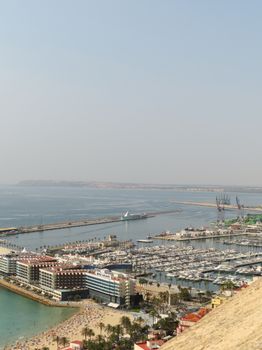 Aerial view of Alicante marina with boats and cityscape during the day.