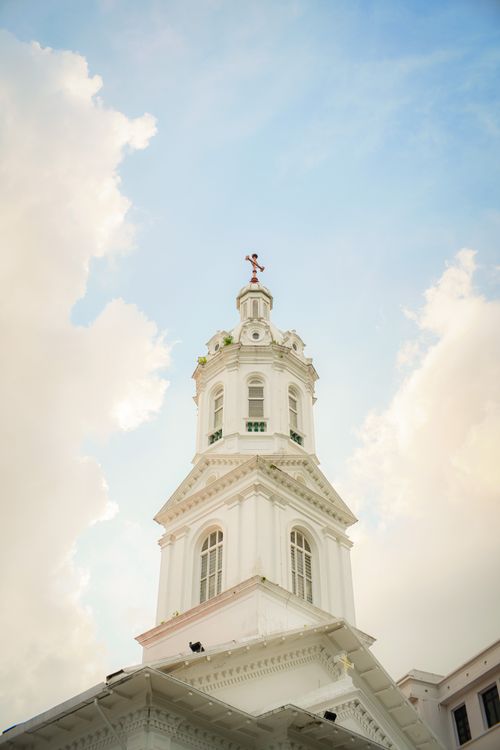Free White clock tower viewed from below amidst bright blue sky and clouds. Stock Photo