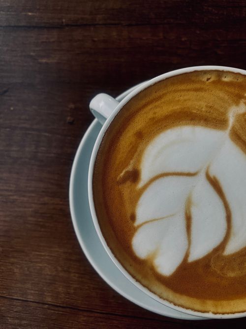 Free Top view of a beautifully crafted latte with leaf design in a white cup on a wooden surface. Stock Photo