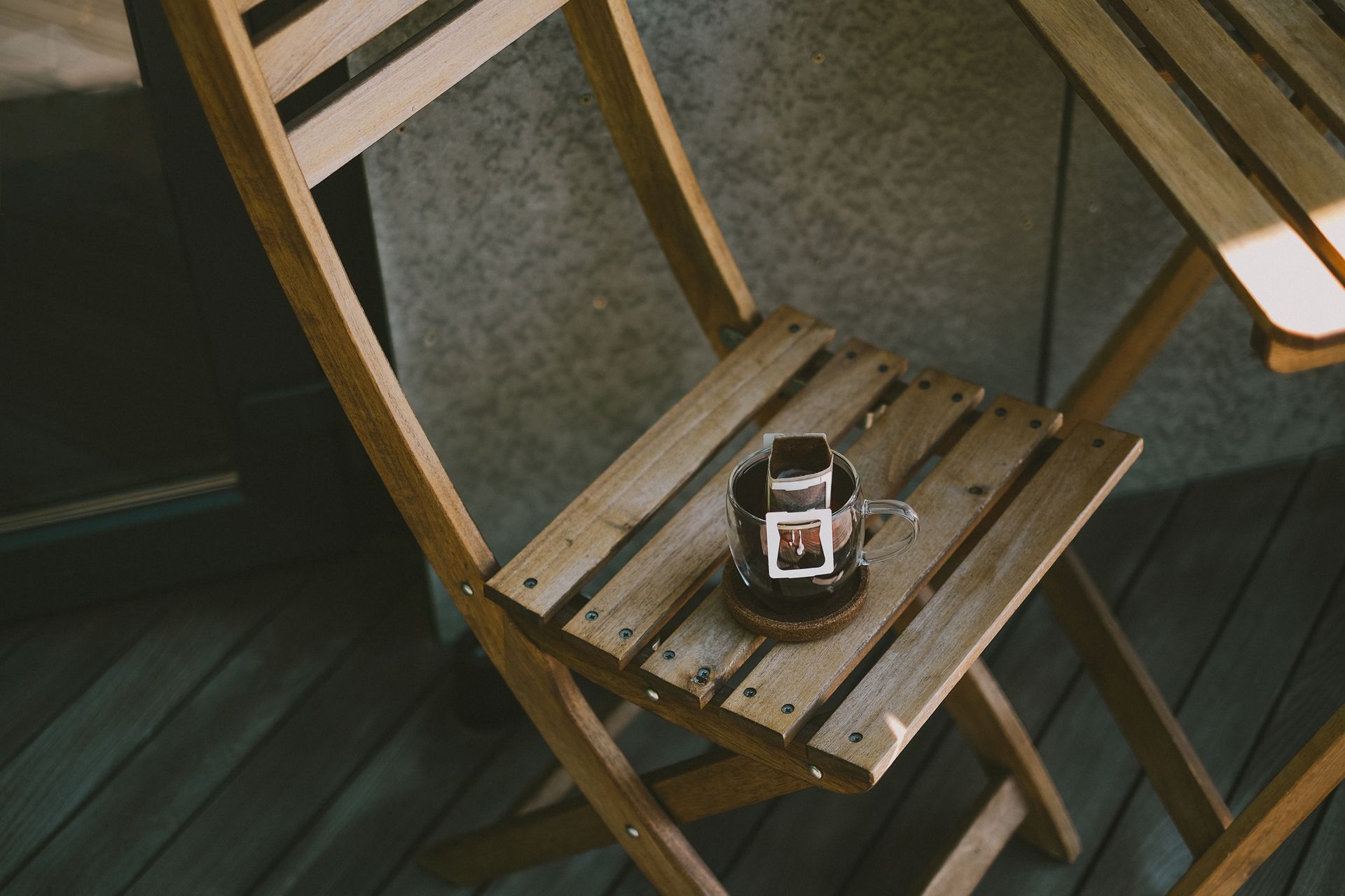 Wooden chair with a drip coffee setup on a terrace, creating a peaceful morning vibe.