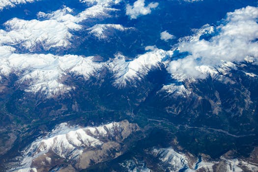 A breathtaking aerial view showcasing majestic snow-capped mountains beneath a blue sky.