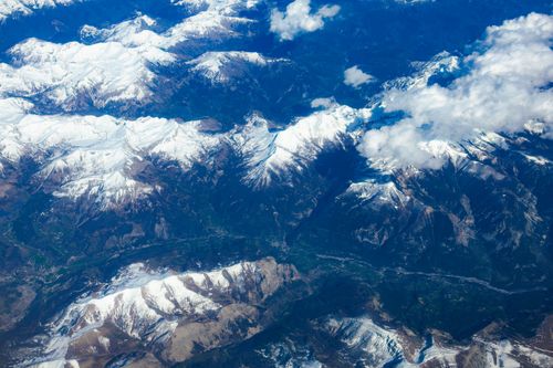 Free A breathtaking aerial view showcasing majestic snow-capped mountains beneath a blue sky. Stock Photo
