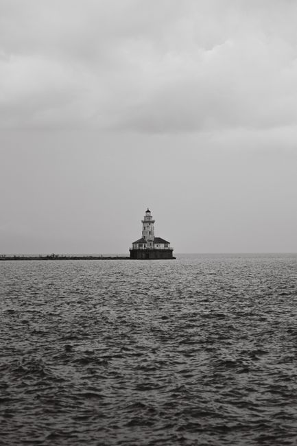 A black and white view of the Chicago Harbor Lighthouse against the vast Lake Michigan.