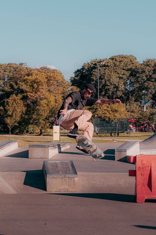 Free Dynamic shot of a skateboarder executing a trick at an outdoor skate park on a sunny day. Stock Photo