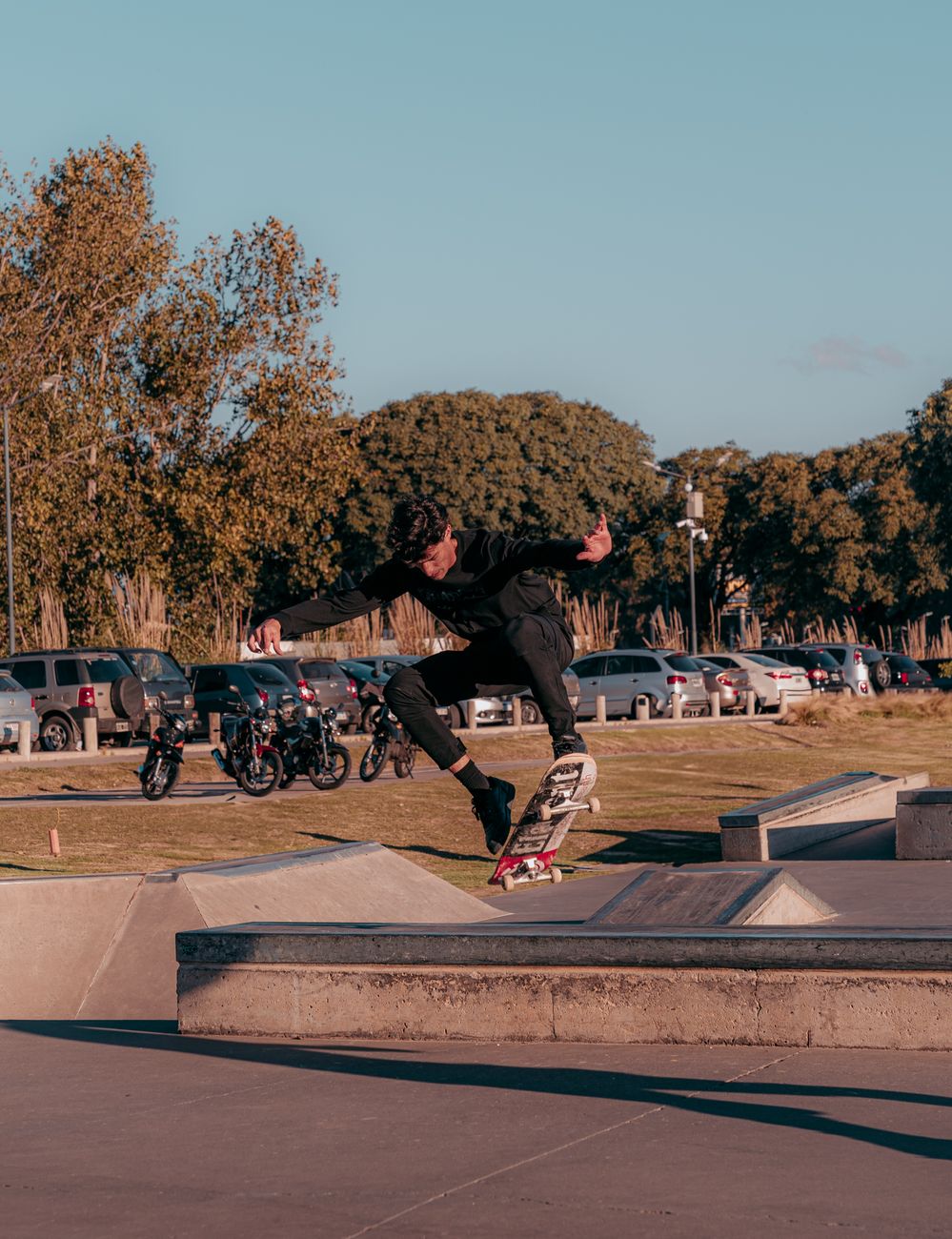 Skateboarder executes trick mid-air at an urban skatepark, showcasing skill and motion.. skateboarder, executes, trick