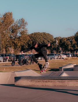 Skateboarder executes trick mid-air at an urban skatepark, showcasing skill and motion.. skateboarder, executes, trick