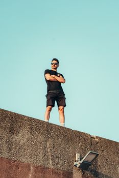 Young man in sunglasses on a rooftop, embodying confidence and urban style.