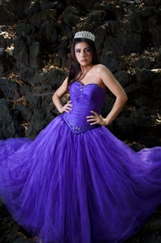 A stunning woman in a purple gown and tiara posing outdoors. Perfect for fashion and glamour themes.