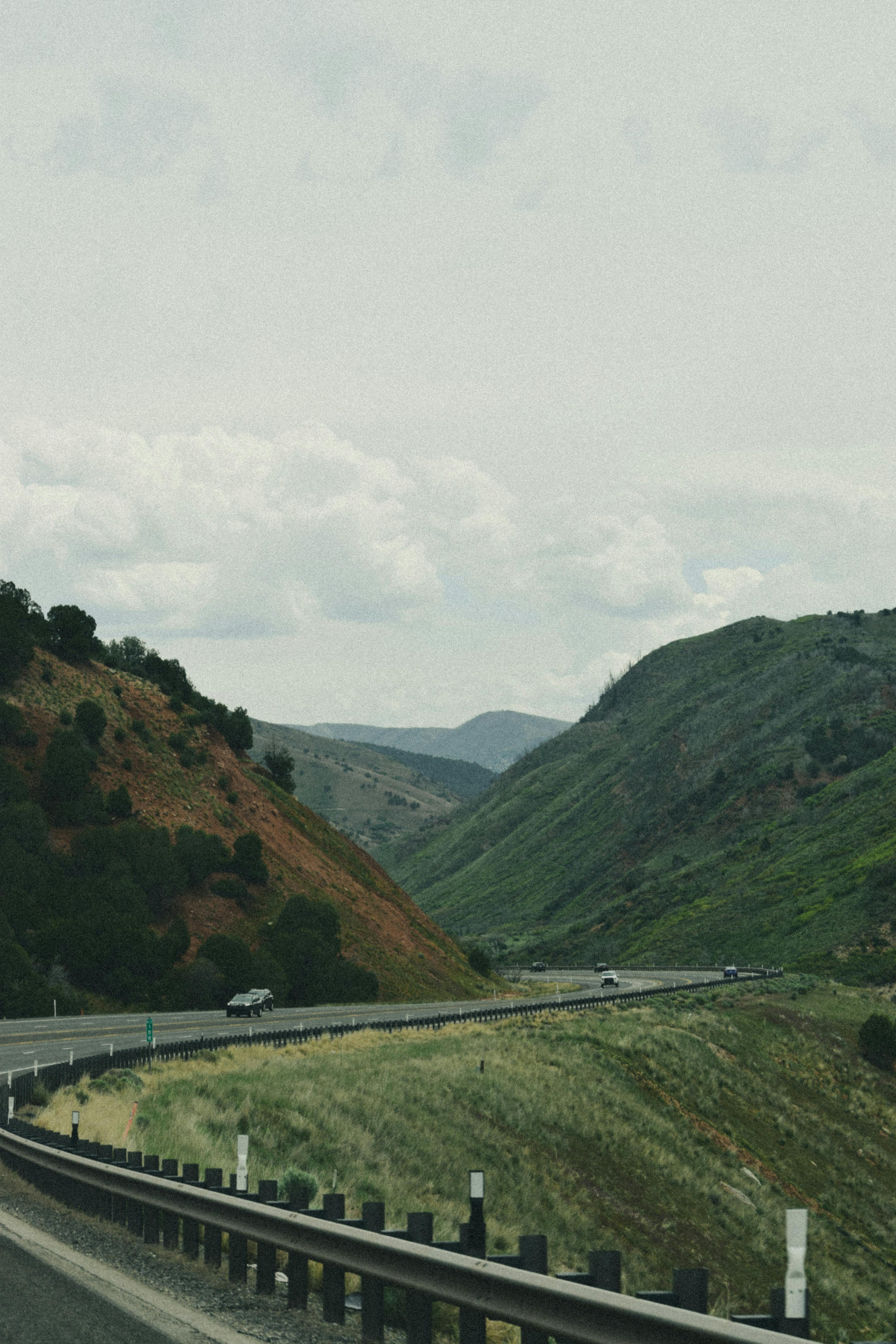Winding road through lush green mountains with cloudy sky, perfect for travel and adventure themes.