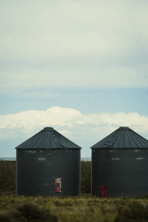 Free Two large grain silos on a rural farm landscape with cloudy skies. Stock Photo