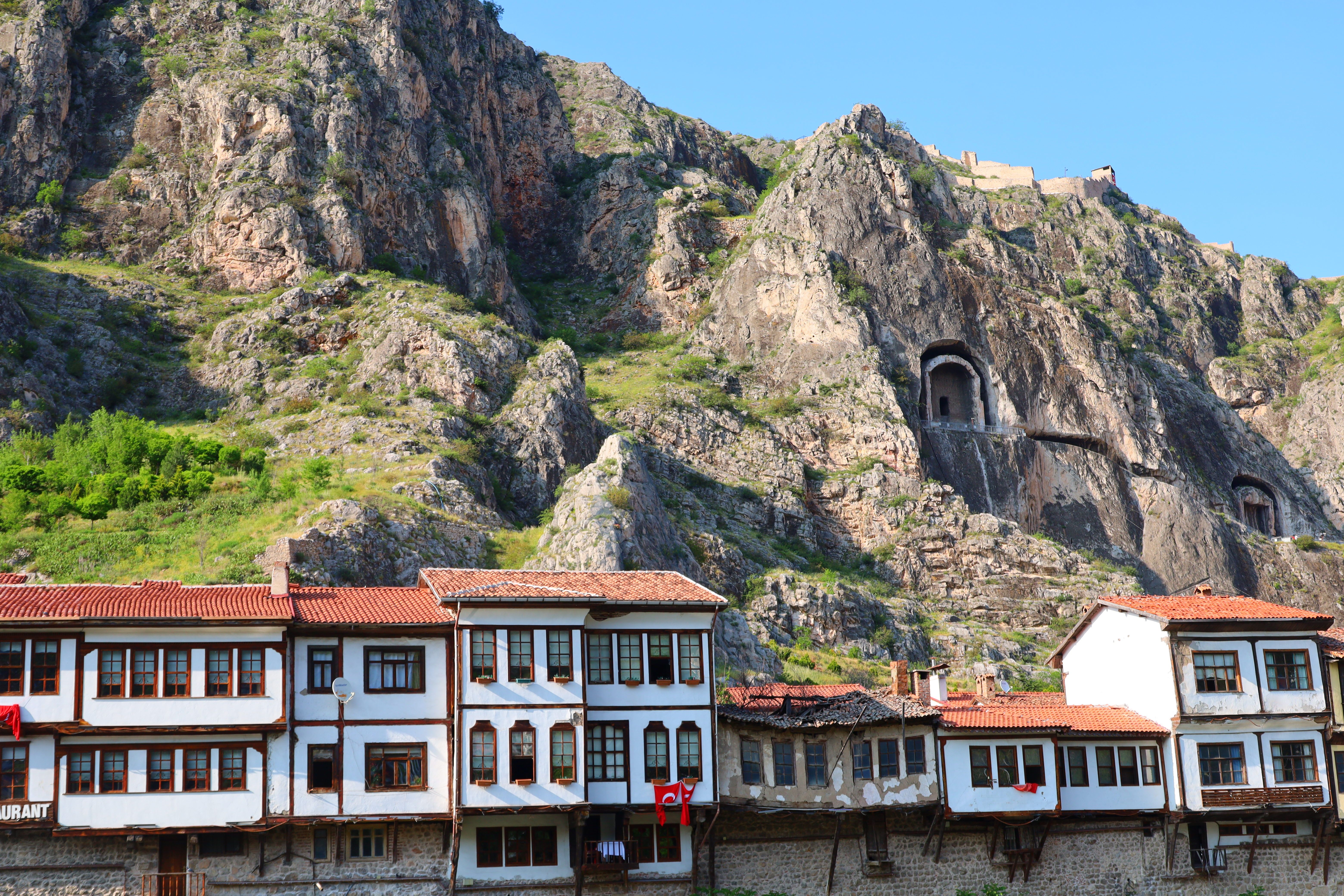 Traditional Ottoman wooden mansions with cumba balconies along Yeşilırmak River at golden hour, Amasya, Turkey, historic architecture with mountain backdrop