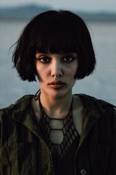 Striking portrait of a young woman with short hair and nose ring in a natural setting.