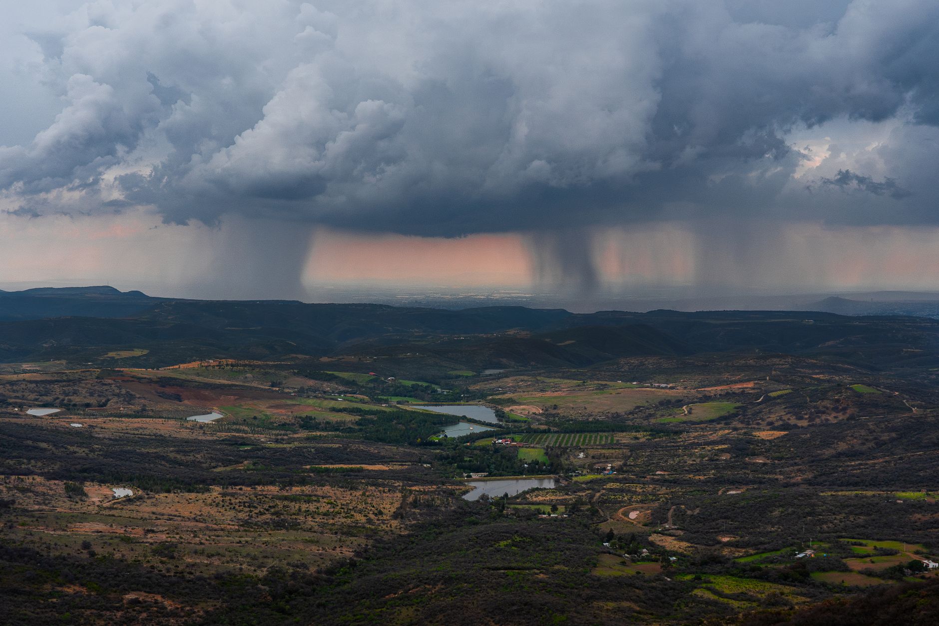 Aerial view of a vast landscape with storm clouds, showcasing the beauty of nature's power.