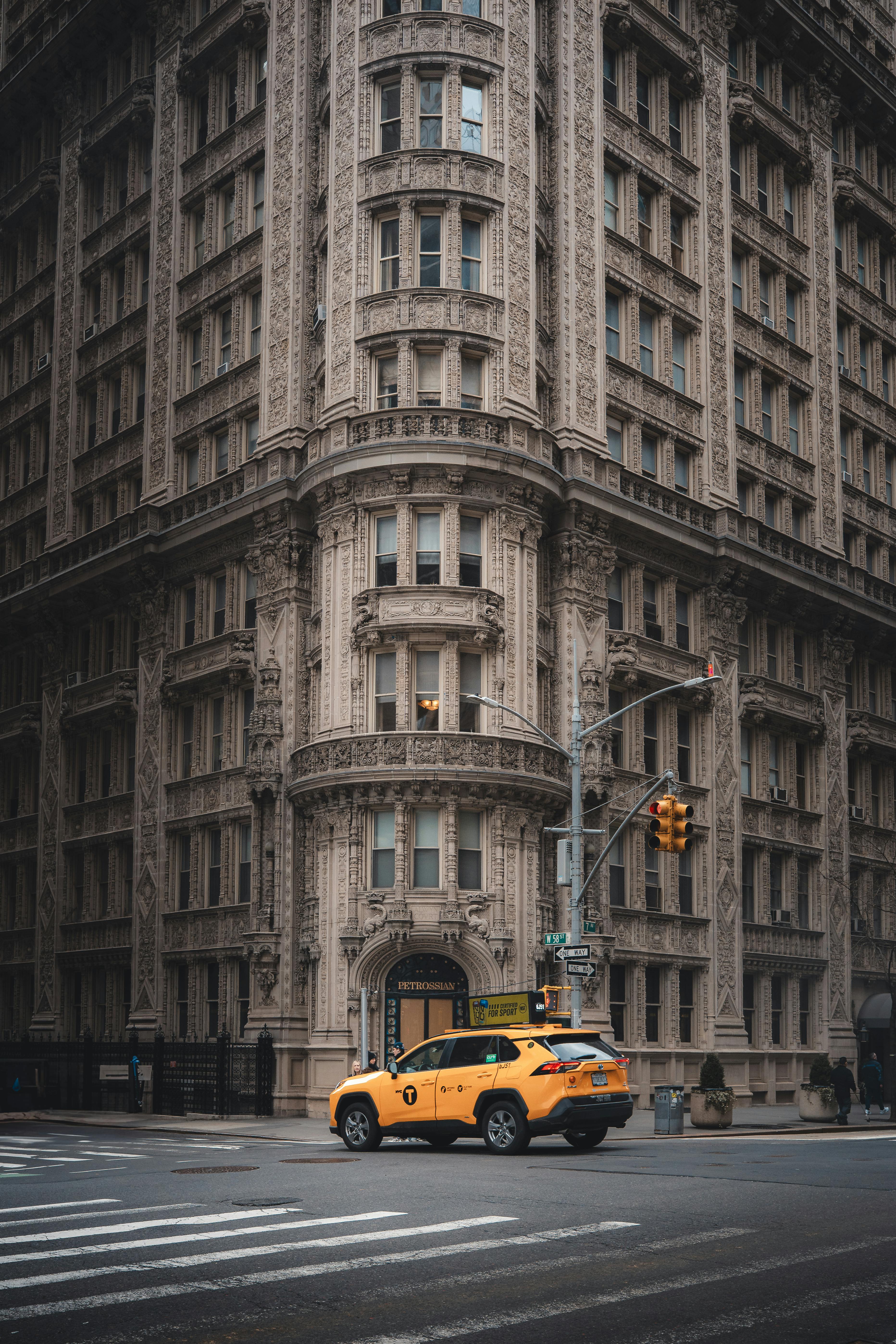 Yellow taxi cab in front of ornate historic building in New York City street.