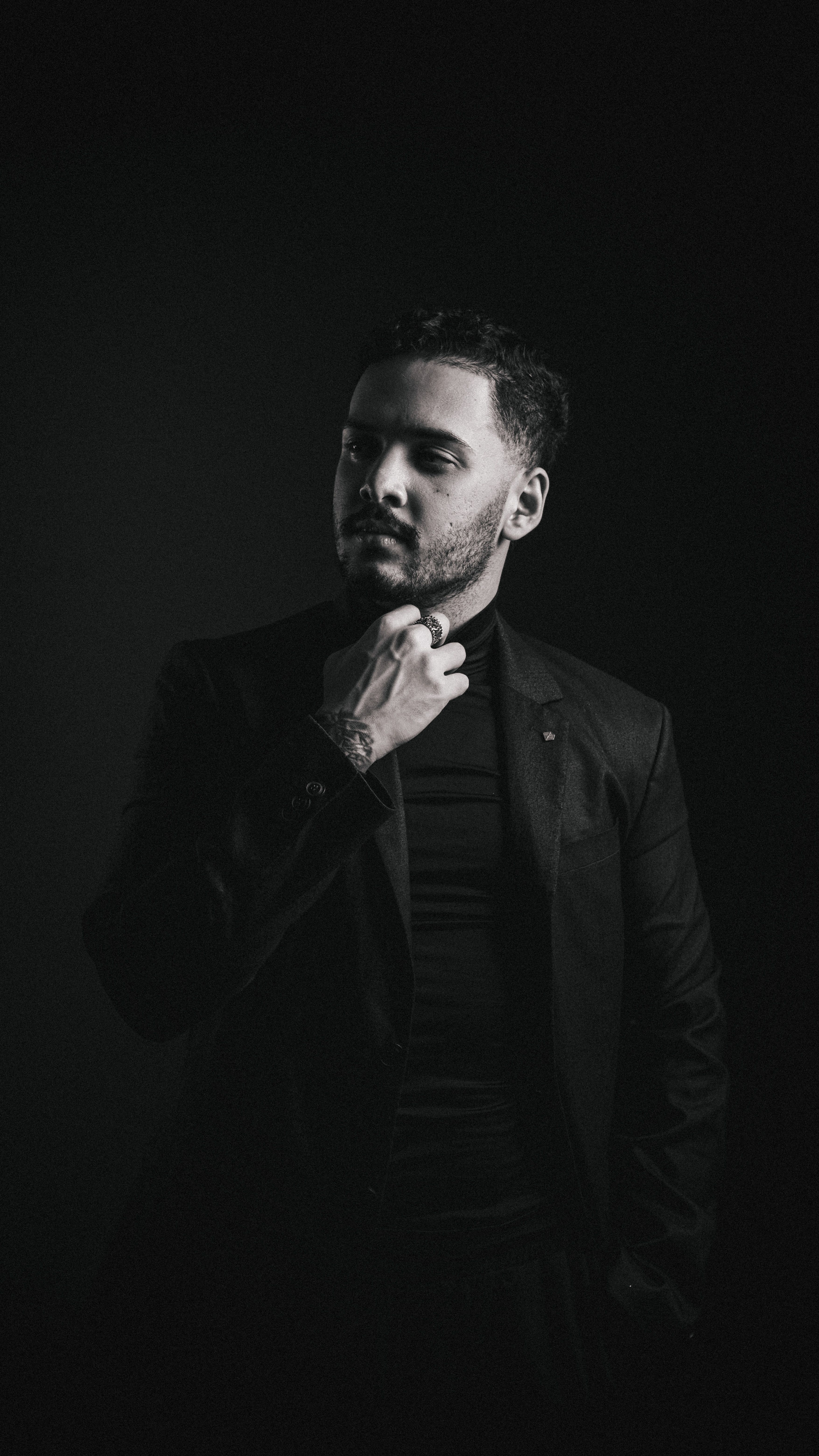 Artistic black and white portrait of a man in a suit with a contemplative expression.