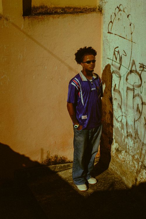 Free A stylish young man in sunglasses stands against a graffitied wall, embodying urban culture and fashion. Stock Photo