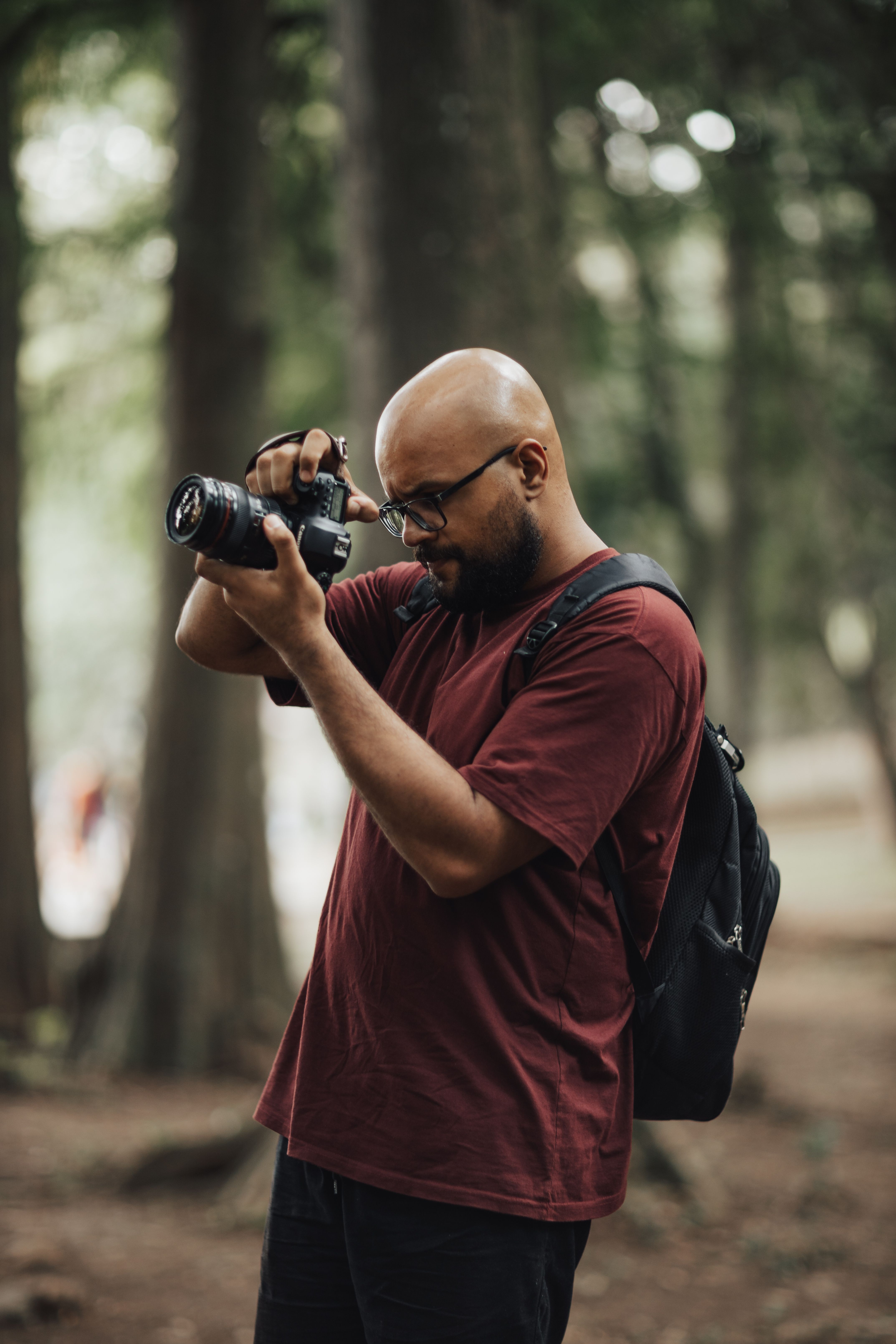 A focused photographer in a forest setting using a DSLR camera.