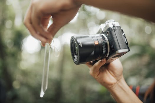 Close-up of a camera and hands in an outdoor setting, showcasing photography tools.
