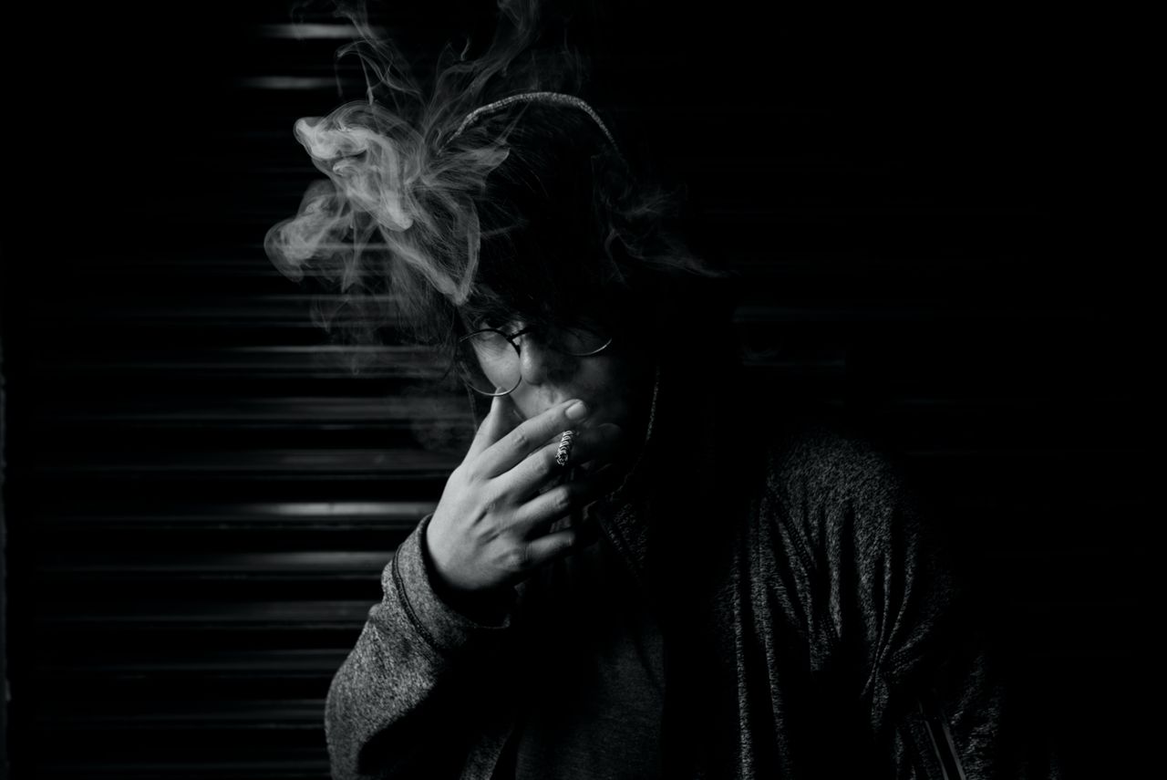 dramatic black and white portrait of a person smoking in low light exu