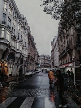 Dramatic view of a rainy street in Europe with classic architecture and people commuting.