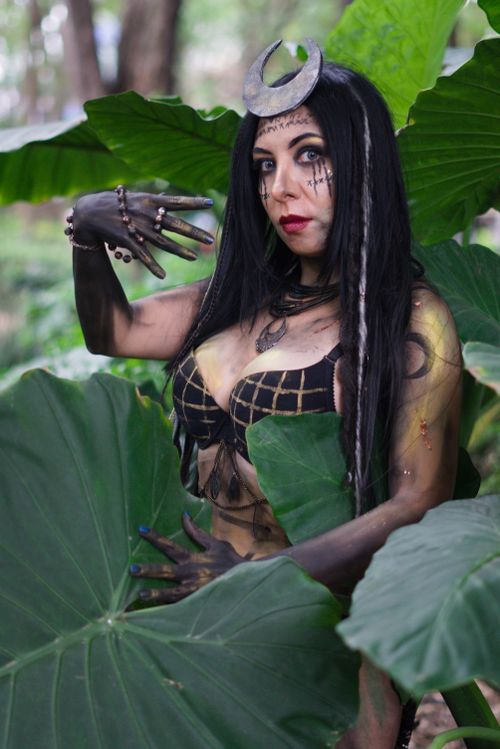 Free A woman with nature-inspired makeup and accessories stands amidst large leaves in an outdoor forest setting. Stock Photo