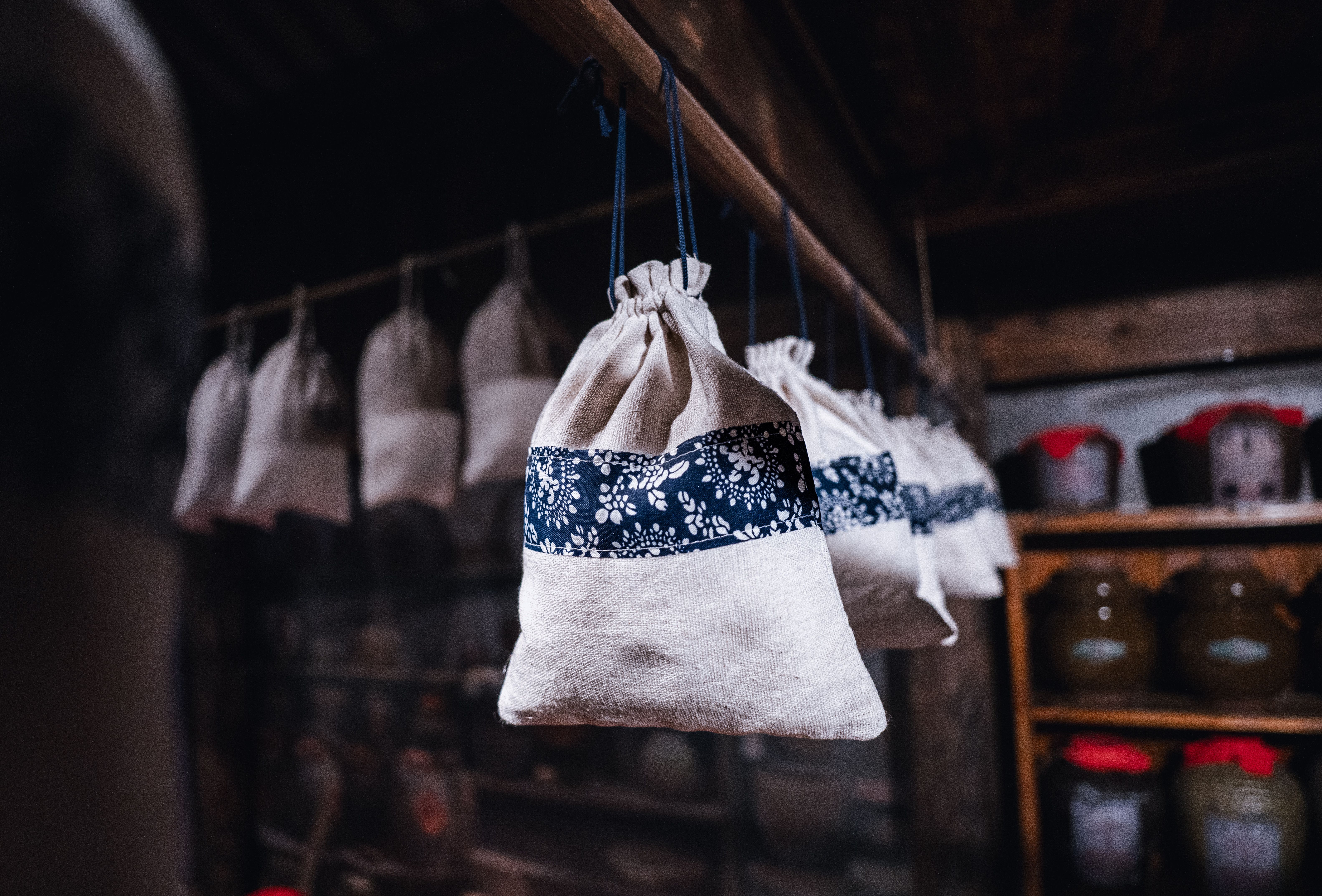 Hanging cloth bags with blue patterns in rustic wooden cabin interior, offering a cozy, vintage feel.