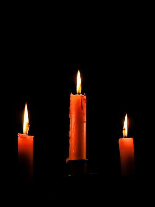 Free Three lit candles in dark setting, creating a warm and serene ambiance. Stock Photo