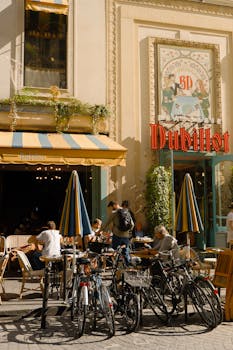 Sunlit outdoor café in Paris with people dining and bicycles parked nearby.