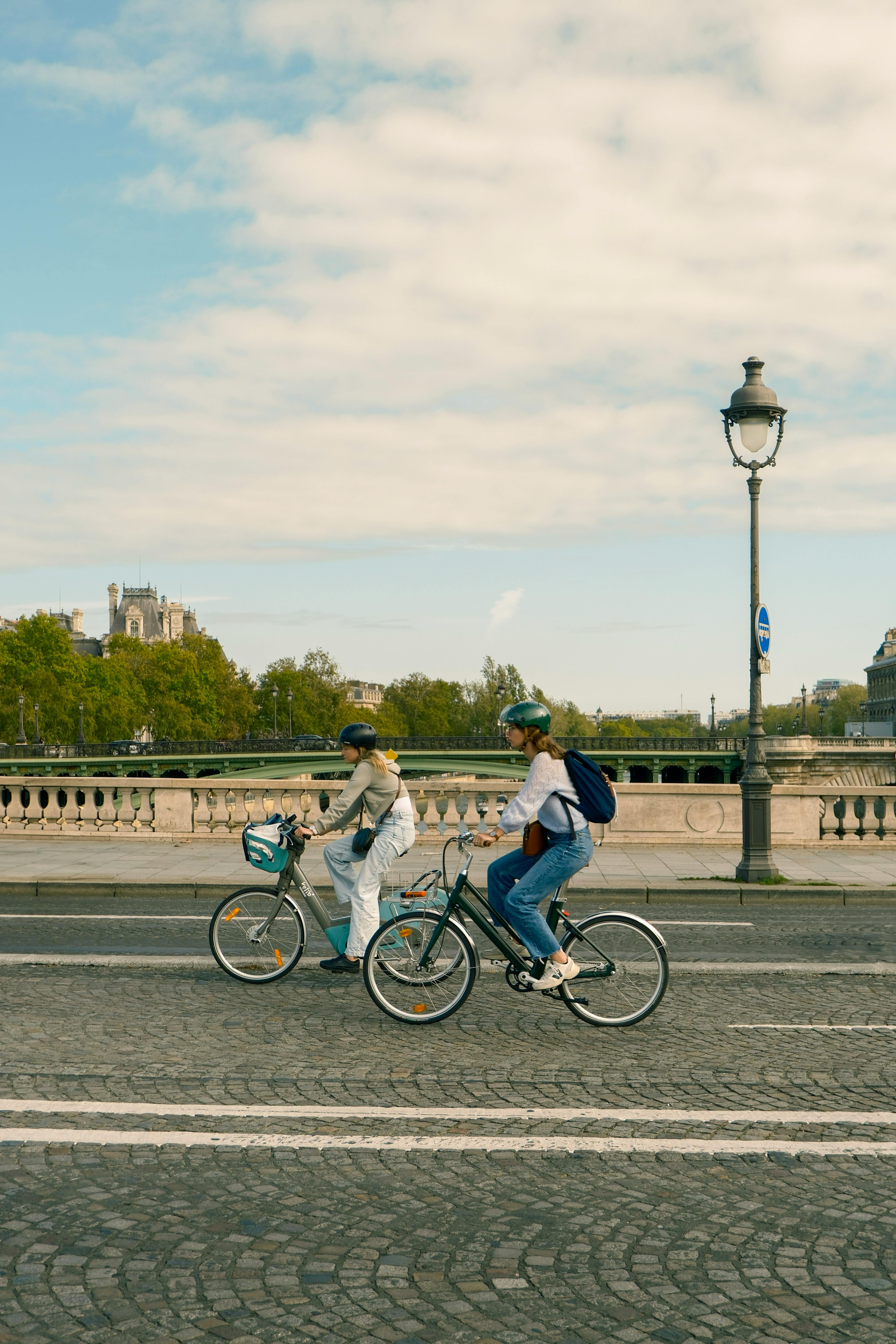 Two cyclists enjoy a leisurely ride along Paris streets with scenic views.