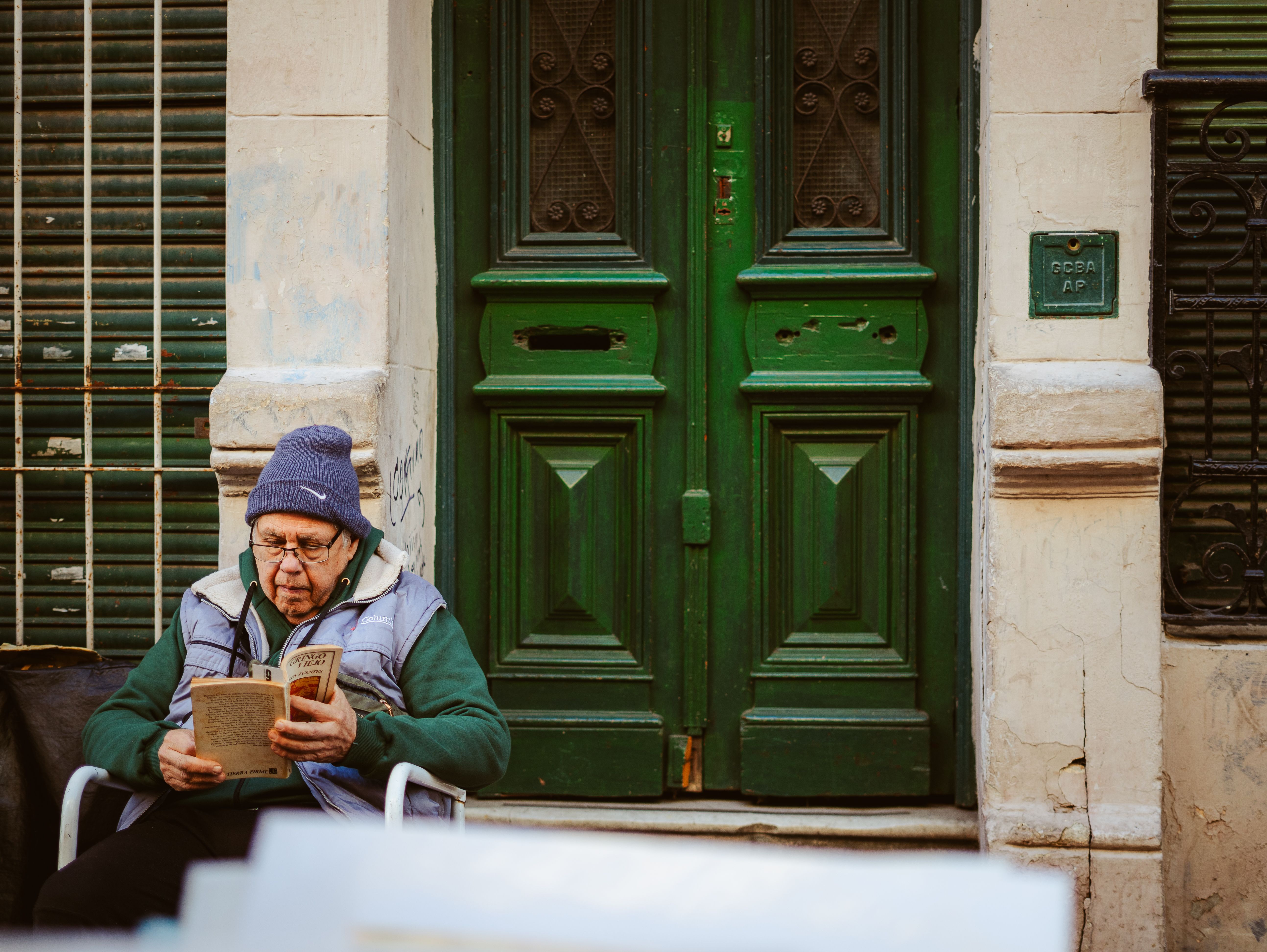 Elderly Man Reading Outside Buenos Aires Doorway · Free Stock Photo