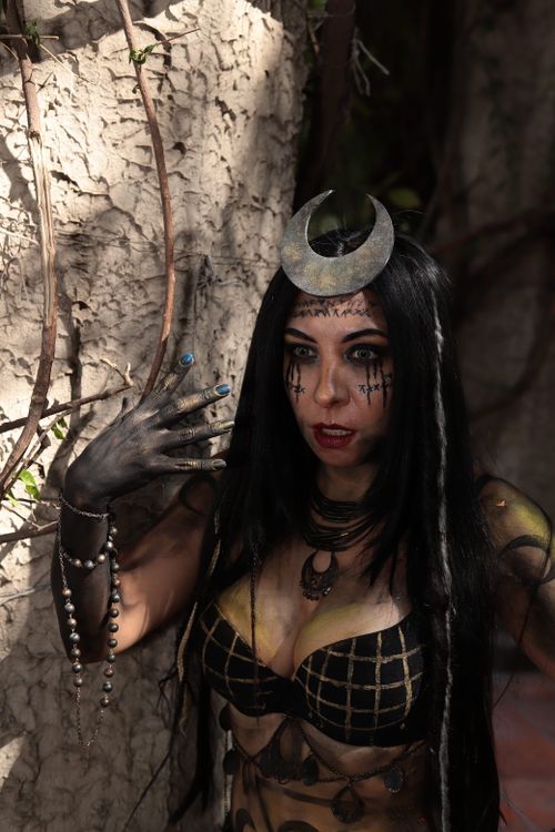 Free A woman in an elaborate dark fantasy costume posing dramatically outdoors with natural light. Stock Photo