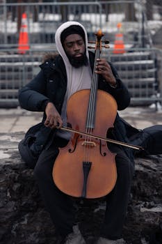 A cellist plays melodies on the street during a cold winter day.