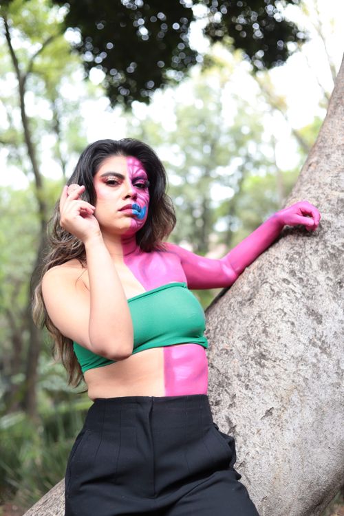 Free A woman with vibrant face and body paint poses outdoors, embracing self-expression and creativity. Stock Photo