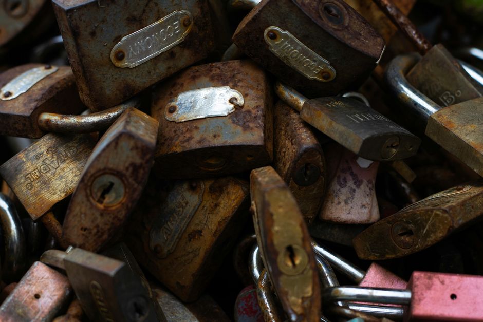 Close-up photo of a pile of rusty padlocks showing textures and aging metal.