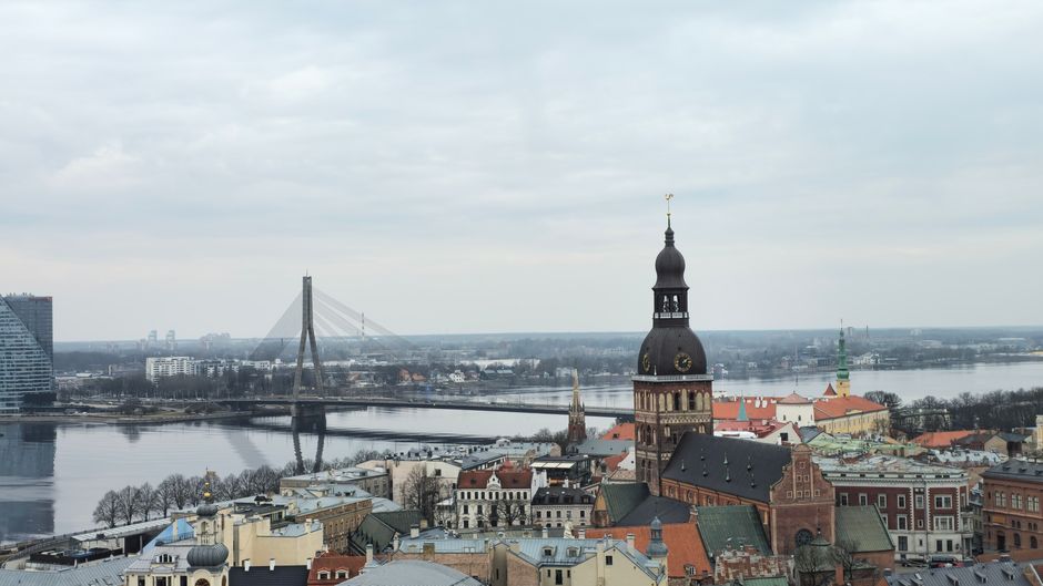 Aerial view of Riga featuring St. Peter's Church and Vanšu Bridge over the Daugava River.